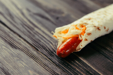 pork sausage and lettuce wrapped in pita bread on wooden background.photo with copy space