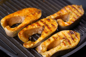Tasty salmon steak, closeup, on a grill pan with herbs. Seafood. Cooking concept. Selective focus
