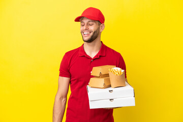 pizza delivery man picking up pizza boxes and burgers over isolated background laughing