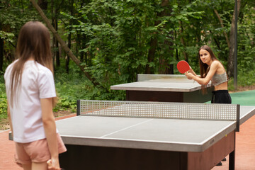 ping pong outdoor, teenager girls playing table tennis with table tennis rackets and ping pong ball