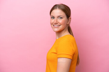 Young caucasian woman wearing band aid isolated on pink background smiling a lot