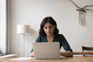 Serious Asian freelance entrepreneur woman using laptop computer for online communication, working...