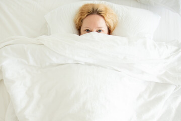 a woman lies under a blanket, does not want to get out of bed, laziness, rest and sleep