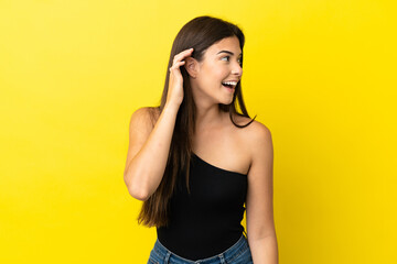 Obraz premium Young Brazilian woman isolated on yellow background listening to something by putting hand on the ear
