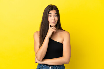 Obraz premium Young Brazilian woman isolated on yellow background and thinking
