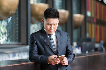 Asian business man wear suit standing using smartphone