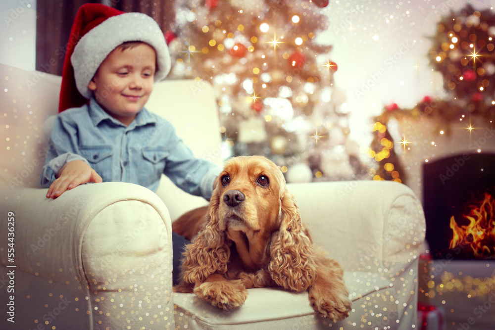 Wall mural cute little boy with english cocker spaniel in room decorated for christmas. magical festive atmosph