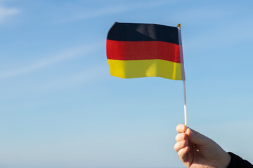 German flag in hand flutters in the wind against the sky, patriotism, Public Holiday, patriotic festival