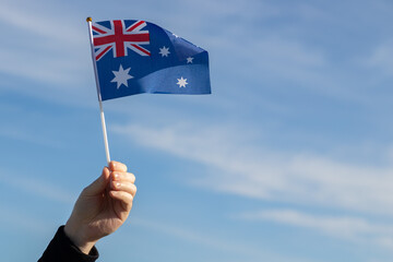Australian flag in hand flutters in the wind against the sky, independence national day of Australia, country freedom, patriotism, Public Holiday, patriotic festival