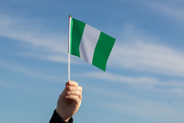 Nigeria flag in hand flutters in the wind against the sky, independence national day of Nigeria,...