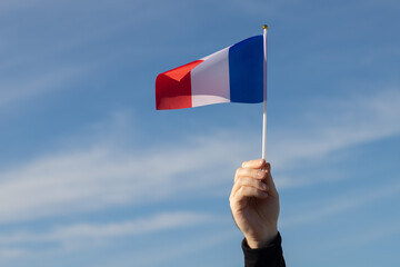 french flag in hand flutters in the wind against the sky, independence national day of france,