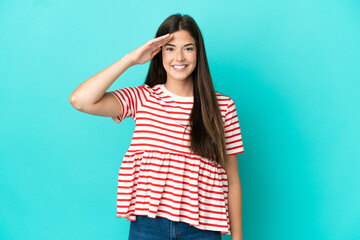 Young Brazilian woman isolated on blue background saluting with hand with happy expression