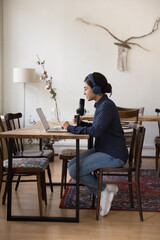 Beautiful Indian radio DJ girl using studio equipment, laptop, microphone, wireless headphones,...