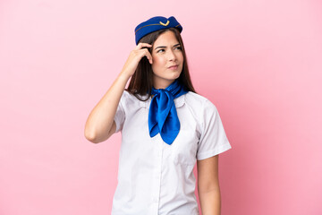 Airplane stewardess Brazilian woman isolated on pink background having doubts and with confuse face expression
