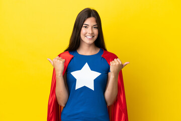 Super Hero Brazilian woman isolated on yellow background with thumbs up gesture and smiling