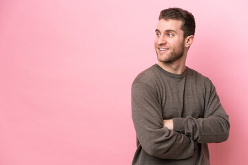 Young caucasian man isolated on pink background looking to the side and smiling