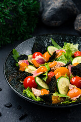 Salad with tuna, lettuce, tomatoes, cucumbers, arugula, nori, tangerines, sesame and mango sauce, closeup.