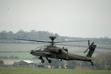 Fototapeta na wymiar close up rear side view of British army AH-64E Boeing Apache Attack helicopter (ZM722 ArmyAir606) hovering, autumn sky, Wiltshire UK
