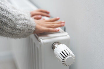 The child's hands warm their hands near the heating radiator. Saving gas in the heating season.