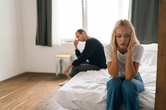 Sad Depressed Stubborn Couple Sitting Separate On Bed Turn Back Ignore Each Other After Fight. Angry Man And Upset Woman Not Talking Showing Selfishness In Bad Relationship. Concept Of Family Problems