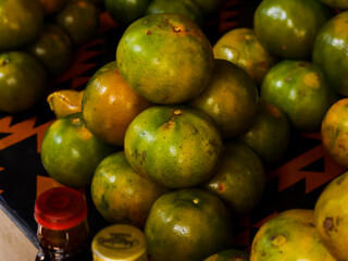 Oranges are yellowish green in a pile on the table, a fruit typical of the tropics, Indonesia