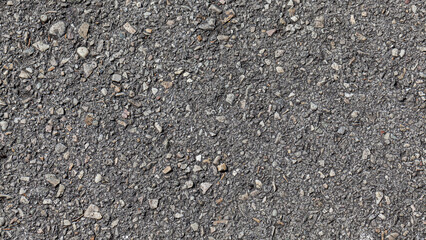 Weathered gray asphalt road texture in the sun, top view. gray tar road texture with rocks, gravel and sand that make up the asphalt with the tar. Copy space