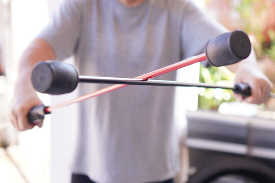 The picture shows a comparison demonstration of the red and black Flexi Bar for toning the abs and upper arms, close up.