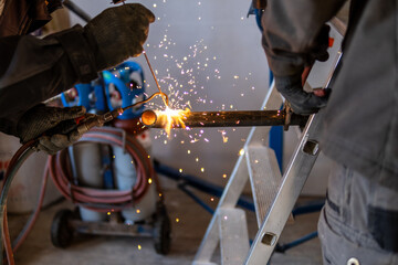 Man welding a gas pipe with flames and sparks