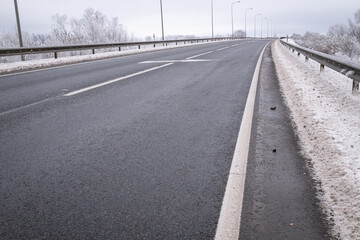 clean wet asphalt road in wintertime. Dirty snow on road sides. Long far perspective. Latvia...
