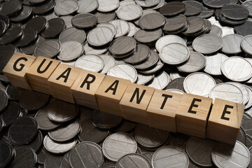 GUARANTEEと書かれたブロックとコイン

