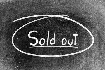 Fototapeta premium White chalk hand writing in word sold out and circle shape on blackboard background