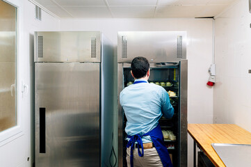 Man storing handmade cheesecakes in the fridge in a small business.