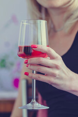 Female hand holding glass of rose wine, closeup