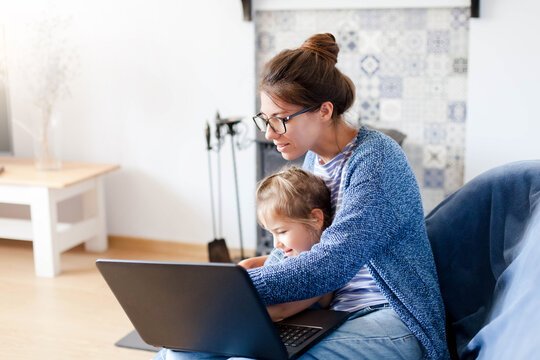 Mother and daughter using laptop, Internet at home. Family healthcare, protection, safety, insurance online. Woman and child gaming virtual. Freelancer workplace for working mom. Technology lifestyle