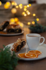 Homemade poppy seed cake, a cup of coffee and fir branches on a rustic board, rolled up traditional Polish poppy seed cake