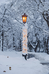 Lantern in the park is covered with snow.