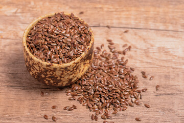 Fototapeta na wymiar flax seeds in a wooden bowl on a wooden background, top view