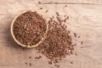 flax seeds in a wooden bowl on a wooden background, top view