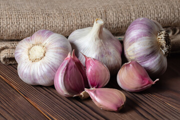 Garlic cloves on wooden table and sackcloth. Fresh peeled garlics and bulbs.