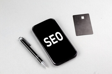 SEO word on smartphone with credit card and pen