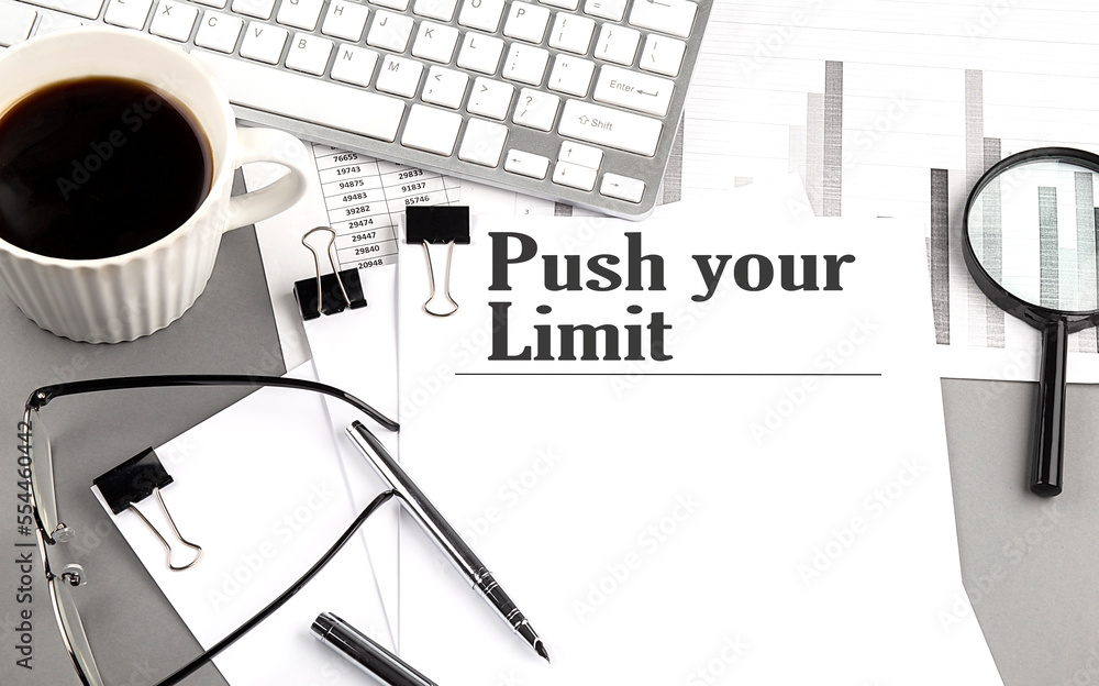 Poster push your limit text on a paper with magnifier, coffee and keyboard on grey background