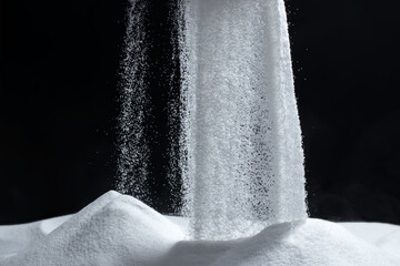 White quartz sand pours on a black background