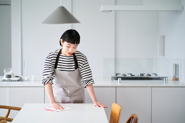 ダイニングテーブルを拭く若い女性