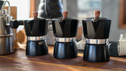 Barista pouring coffee from mocha pot coffee maker to a coffee cup. Hand holding Italian classic mocha pot pouring coffee.