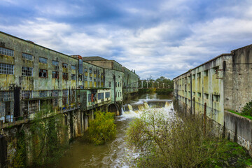 Old abandoned Matrena factory in the river margins with a little waterfall. Old factory in the margins of the Nabao river in the city of Tomar - Portugal