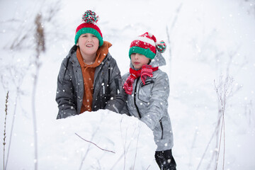 Two boys are playing in the snow. Children sculpt from snow. Play on a winter day in nature.