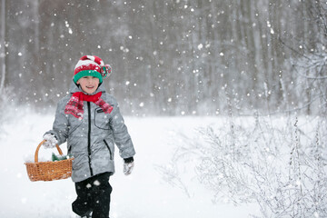 A boy walks in the winter forest with a Christmas basket.