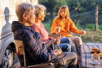 Family aunty mom daughter on holiday travel camper van sit on chair drink morning coffee relaxation