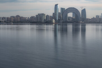 Modern city skyline with skyscrapers on a seafront reflected in still water, Baku, Azerbaijan
