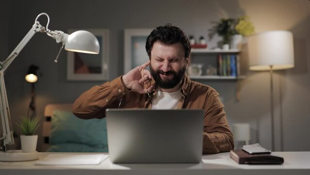 Itching in ear. Man intensively scratches his ear. Bearded middle aged male worker with otitis media feels discomfort and burning sensation in his ear